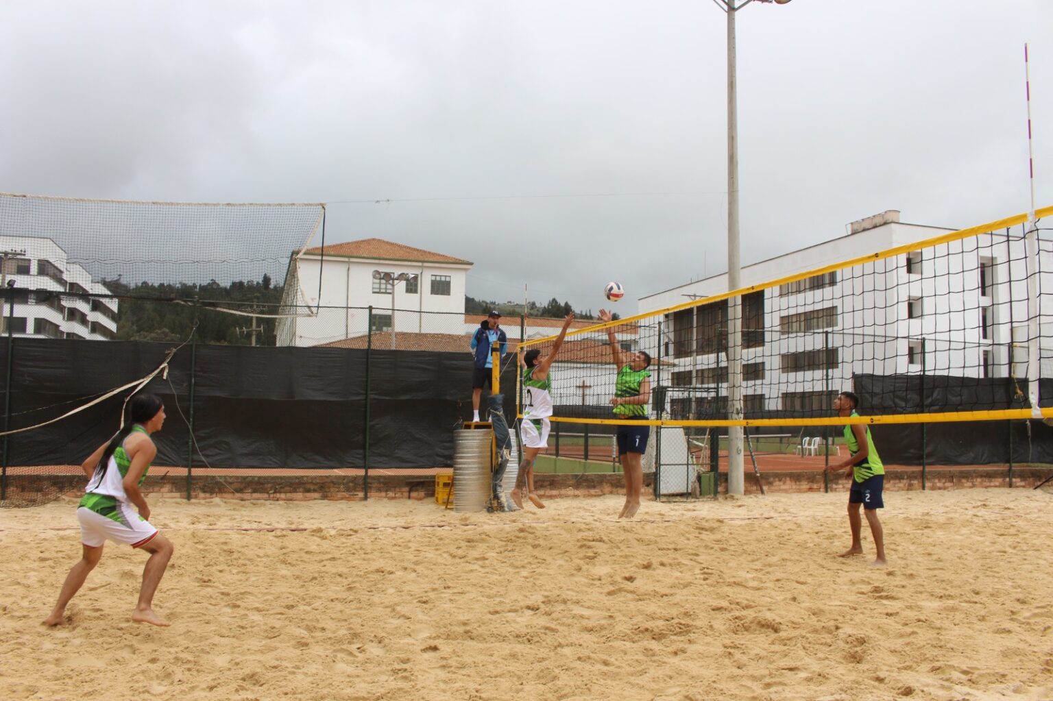 Foto de dos equipos de estudiantes jugando voleibol en una cancha de arena